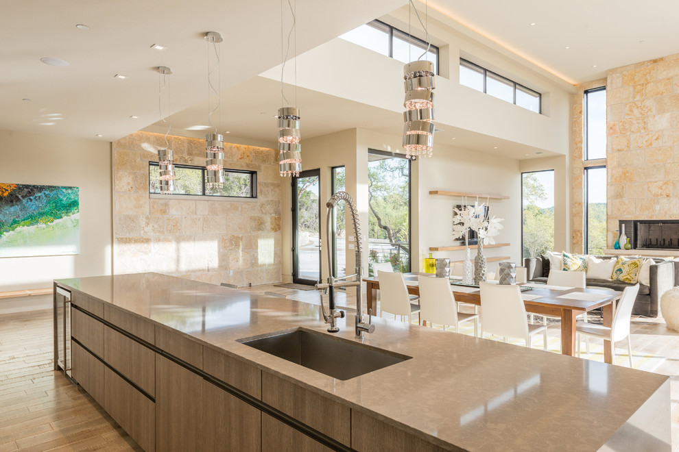 Contemporary galley open plan kitchen in Austin with an undermount sink, flat-panel cabinets, light wood cabinets, quartz benchtops, white splashback and with island.