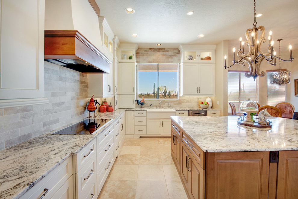 Example of a large transitional u-shaped travertine floor and beige floor open concept kitchen design in Phoenix with a farmhouse sink, recessed-panel cabinets, white cabinets, granite countertops, gray backsplash, porcelain backsplash, stainless steel appliances, an island and multicolored countertops