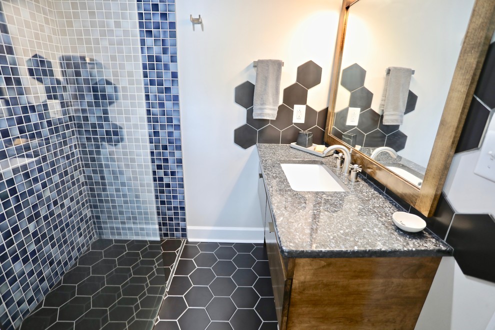 Small midcentury master bathroom in Raleigh with flat-panel cabinets, medium wood cabinets, a curbless shower, blue tile, ceramic tile, beige walls, ceramic floors, an undermount sink, granite benchtops, black floor, an open shower and blue benchtops.