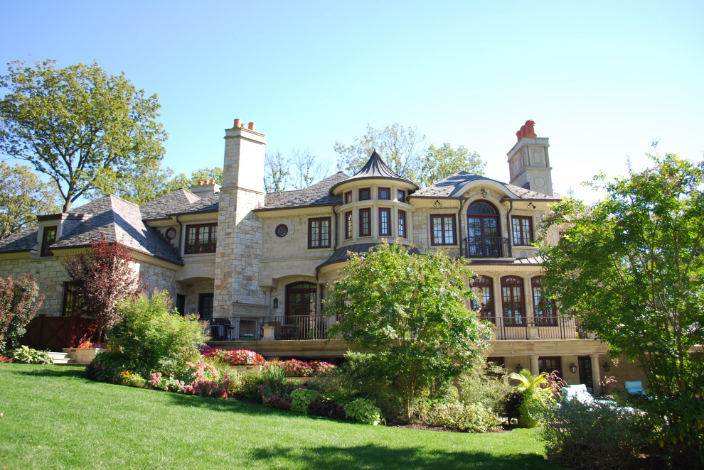 Immagine della villa ampia beige classica a tre piani con rivestimento in pietra, tetto a padiglione, copertura in tegole e tetto grigio