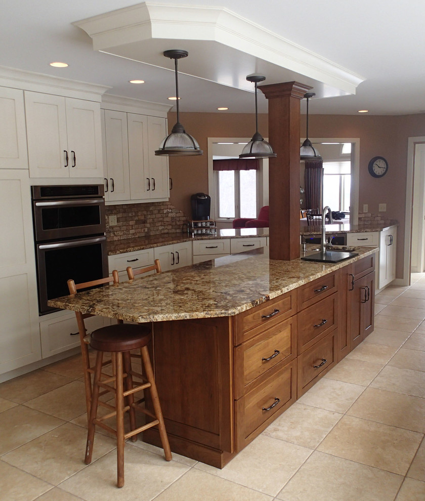 Eat-in kitchen - large rustic ceramic tile eat-in kitchen idea in Bridgeport with an undermount sink, shaker cabinets, granite countertops, beige backsplash, stone tile backsplash, stainless steel appliances and an island