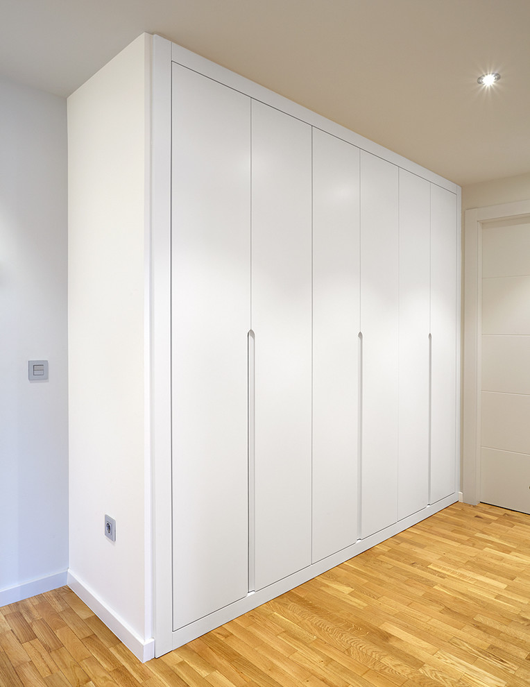 Mid-sized transitional gender-neutral built-in wardrobe in Other with flat-panel cabinets, white cabinets and medium hardwood floors.