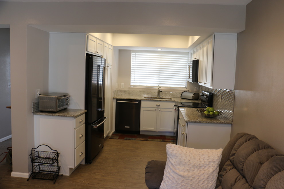 Small transitional u-shaped vinyl floor and brown floor eat-in kitchen photo in Denver with an undermount sink, recessed-panel cabinets, white cabinets, granite countertops, gray backsplash, ceramic backsplash, black appliances, no island and white countertops