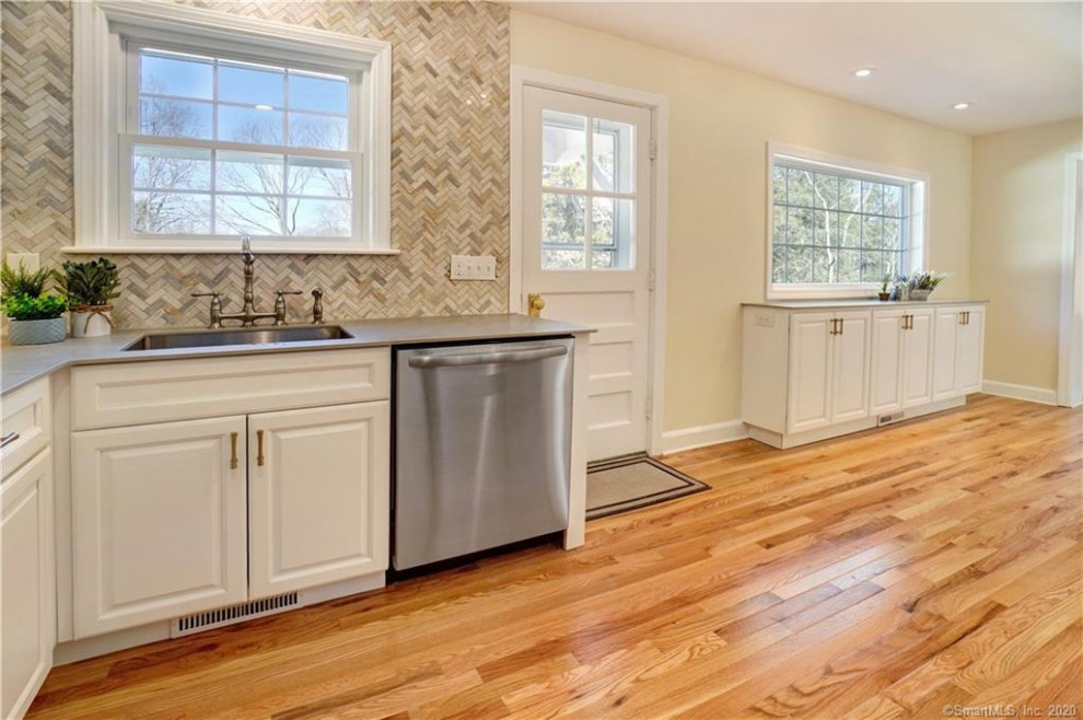 Inspiration for a mid-sized transitional l-shaped light wood floor eat-in kitchen remodel with an undermount sink, shaker cabinets, white cabinets, marble backsplash, stainless steel appliances and gray countertops