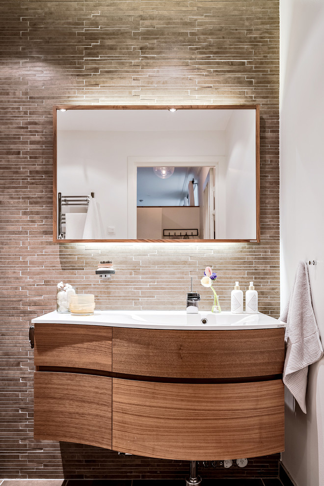 Photo of a contemporary bathroom in Gothenburg with flat-panel cabinets, medium wood cabinets, brown tile, matchstick tile, white walls, an integrated sink and brown floor.