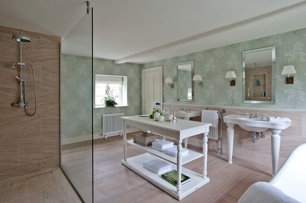 This is an example of a country bathroom in London with a console sink, a freestanding tub, an open shower, beige tile, multi-coloured walls, light hardwood floors and an open shower.