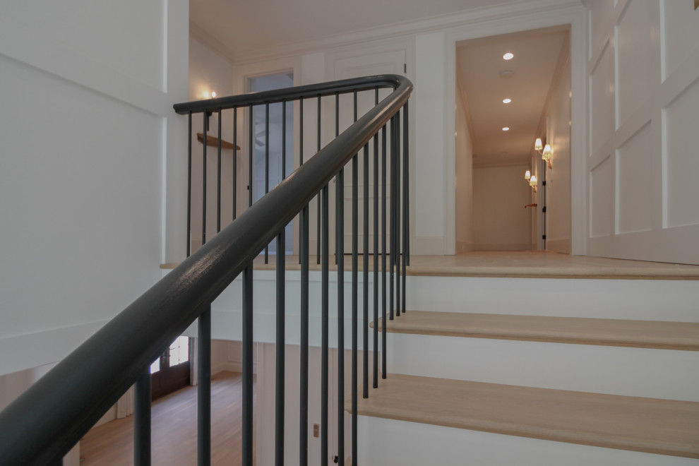 Large modern wood u-shaped mixed railing staircase in DC Metro with painted wood risers and wainscoting.