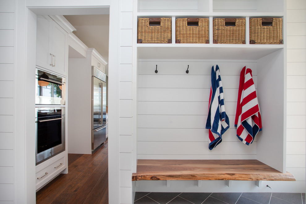 This is an example of a mid-sized beach style mudroom in Other with white walls and grey floor.
