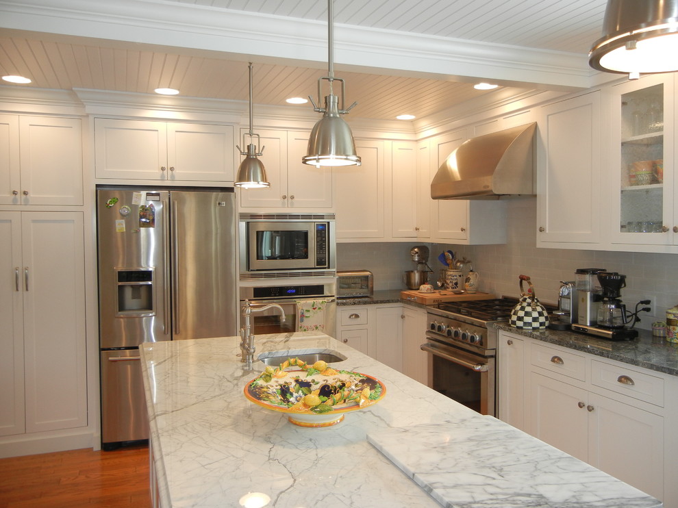 Open concept kitchen - large transitional u-shaped medium tone wood floor, brown floor and shiplap ceiling open concept kitchen idea with shaker cabinets, white cabinets, stainless steel appliances, an island, white backsplash, subway tile backsplash, granite countertops and an undermount sink
