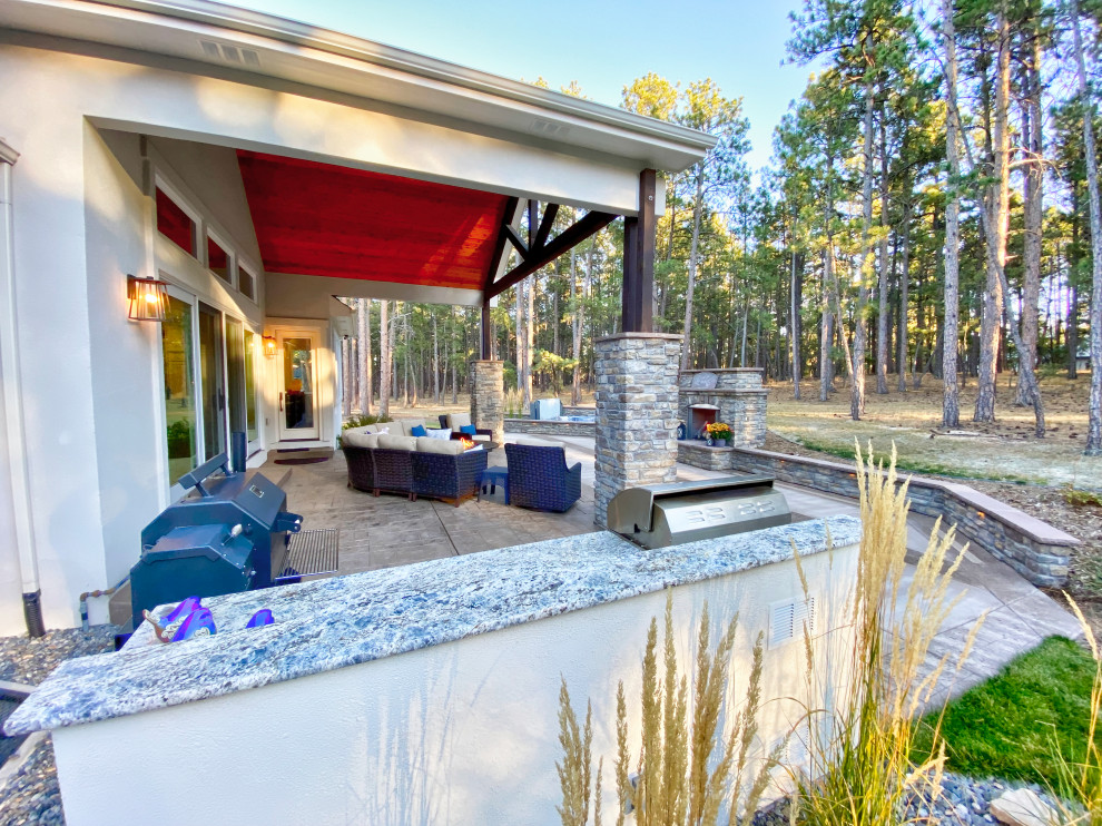 Foto di un grande patio o portico classico dietro casa con un caminetto, cemento stampato e un tetto a sbalzo