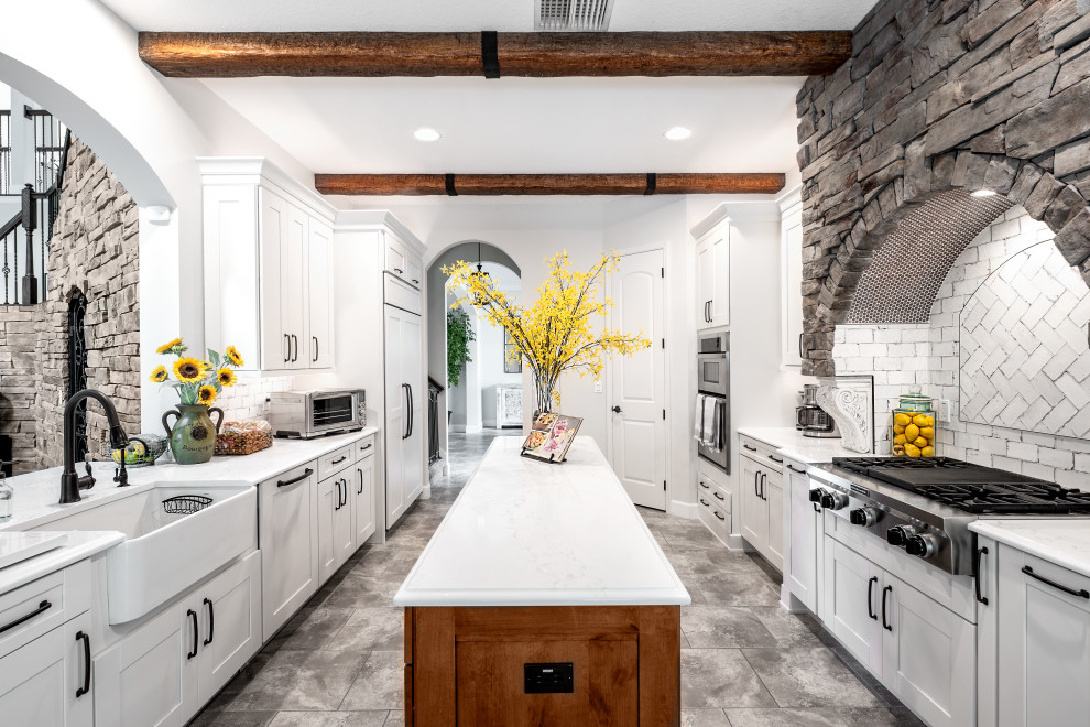 Inspiration for a large transitional separate kitchen in Tampa with a farmhouse sink, shaker cabinets, white cabinets, quartz benchtops, white splashback, stainless steel appliances, porcelain floors, with island, grey floor and white benchtop.