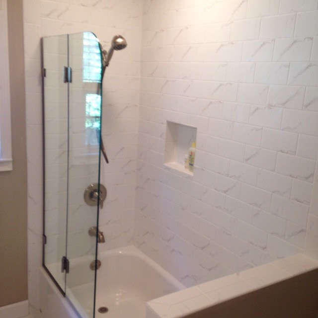 Mid-sized transitional white tile and porcelain tile corner bathtub photo with beige walls and a hinged shower door