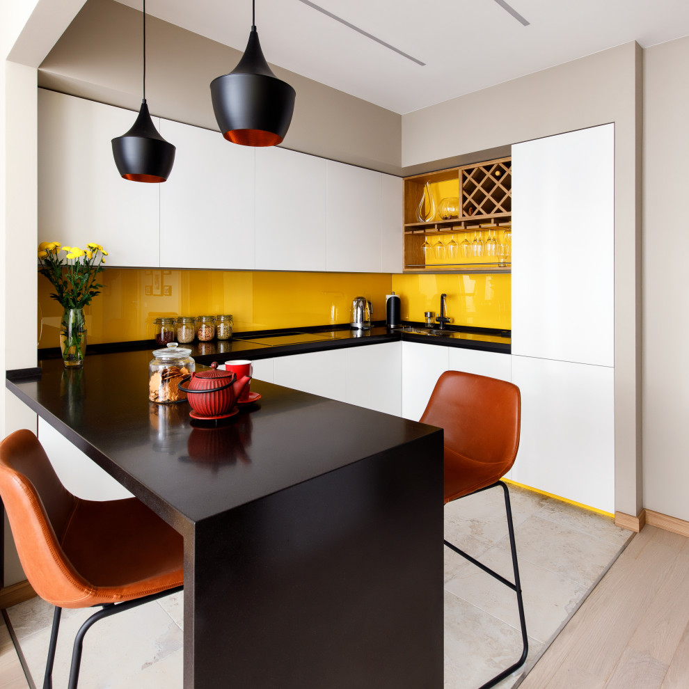 Mid-sized contemporary u-shaped eat-in kitchen in Moscow with a single-bowl sink, white cabinets, solid surface benchtops, yellow splashback, glass sheet splashback, panelled appliances and black benchtop.