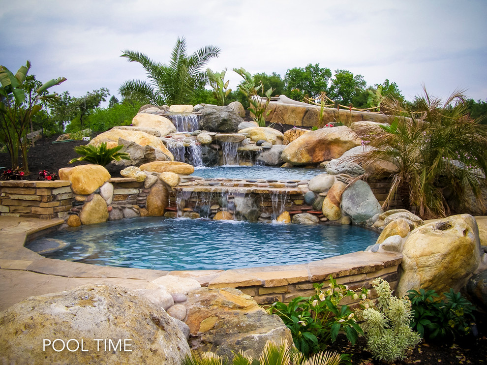 Inspiration for a large contemporary backyard custom-shaped pool in Sacramento with a water slide and natural stone pavers.