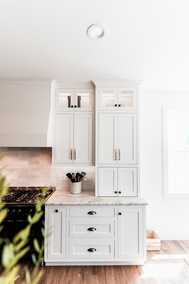 Example of a large transitional l-shaped light wood floor open concept kitchen design with an undermount sink, shaker cabinets, white cabinets, quartzite countertops, multicolored backsplash, porcelain backsplash, stainless steel appliances and an island