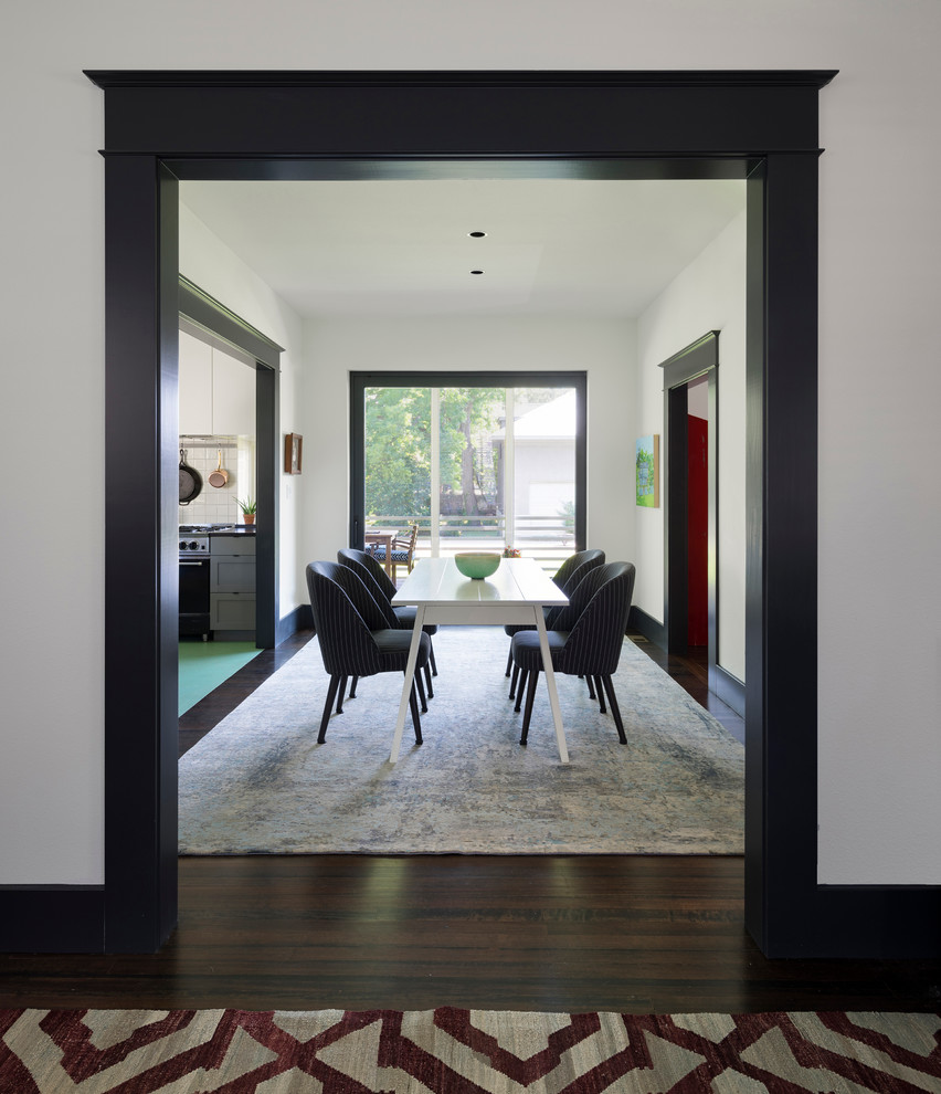 This is an example of a transitional kitchen/dining combo in Austin with white walls and dark hardwood floors.