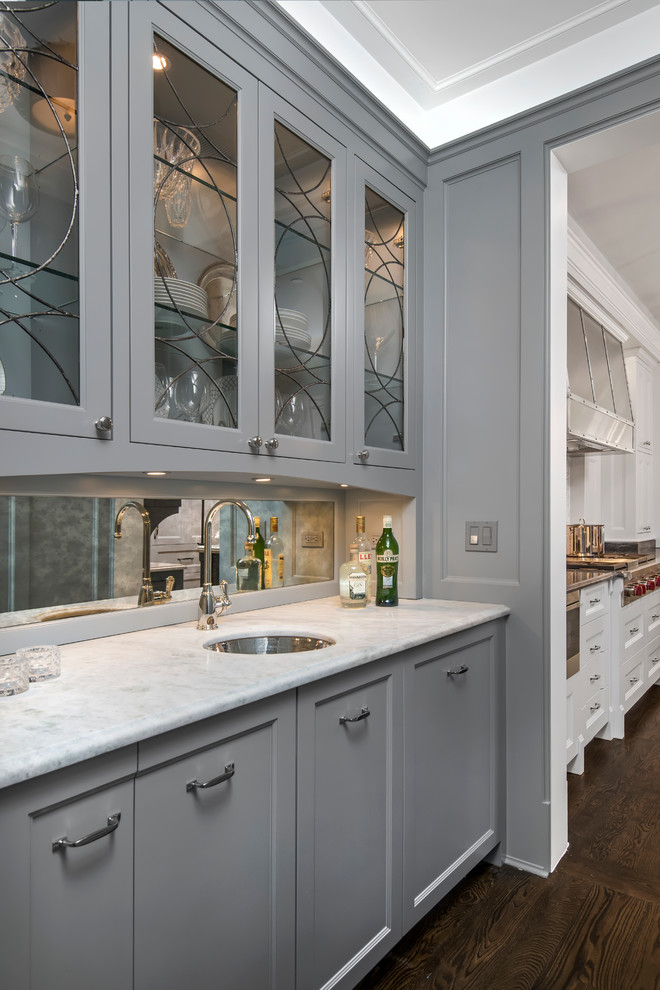 This is an example of a small traditional single-wall wet bar in Chicago with an undermount sink, grey cabinets, dark hardwood floors and mirror splashback.