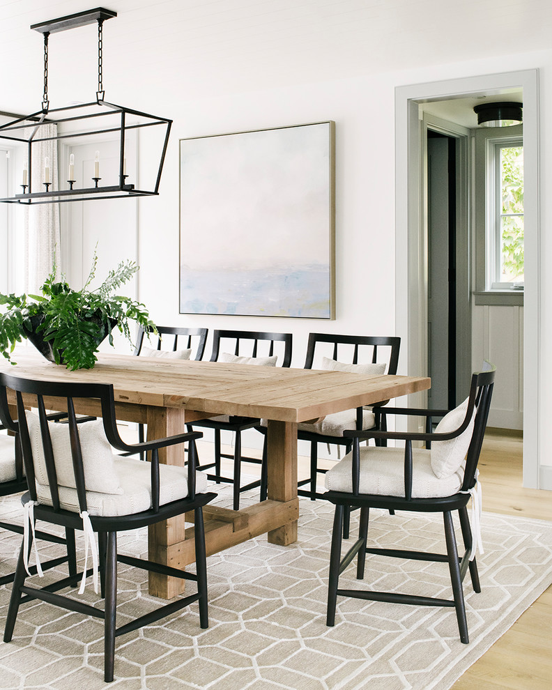 This is an example of a beach style dining room in Los Angeles with white walls and light hardwood floors.
