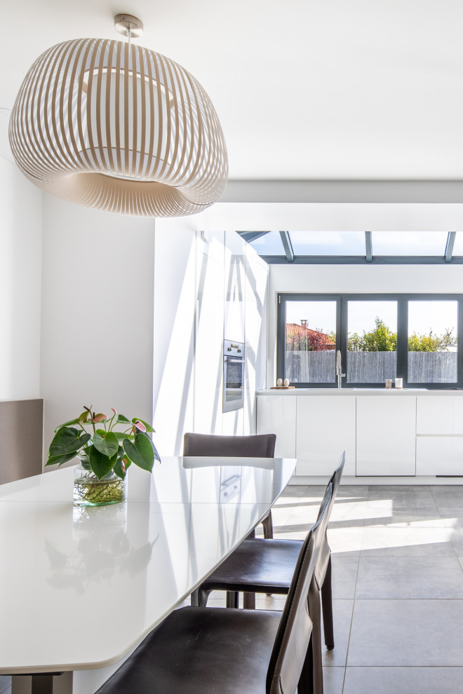Inspiration pour une salle à manger ouverte sur le salon minimaliste de taille moyenne avec un mur blanc, un sol gris et verrière.