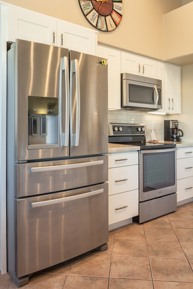 Example of a transitional galley ceramic tile open concept kitchen design in Phoenix with an undermount sink, recessed-panel cabinets, white cabinets, quartz countertops, white backsplash, ceramic backsplash, stainless steel appliances and an island