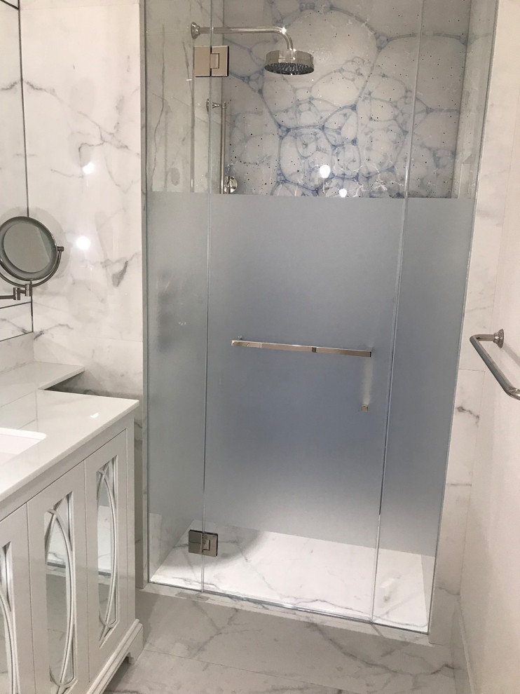 This is an example of a small transitional 3/4 bathroom in New York with furniture-like cabinets, white cabinets, a curbless shower, a one-piece toilet, white tile, marble, white walls, marble floors, an undermount sink, marble benchtops, white floor, a hinged shower door, white benchtops, a shower seat, a single vanity and a freestanding vanity.