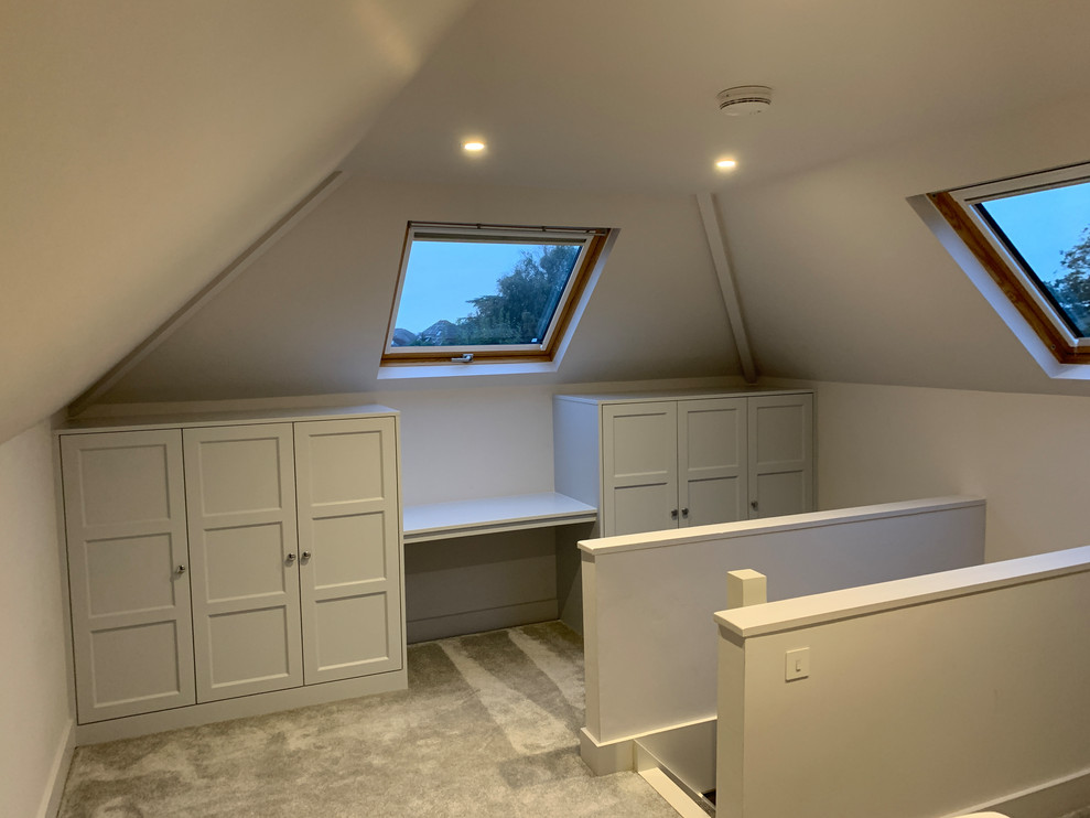 This is an example of a mid-sized beach style gender-neutral dressing room in Dorset with shaker cabinets, grey cabinets, carpet and grey floor.