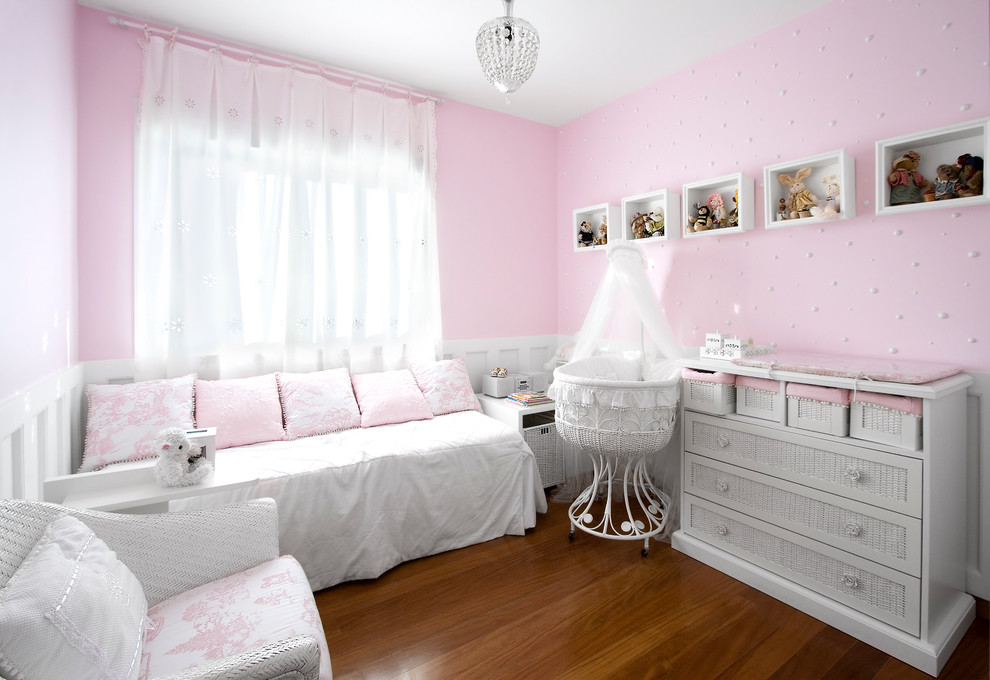 Design ideas for a mid-sized transitional nursery for girls in Other with pink walls and medium hardwood floors.