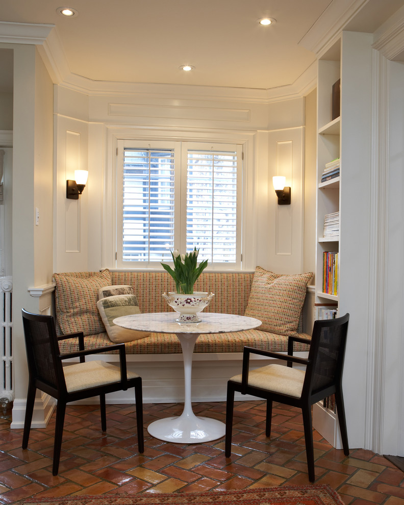 This is an example of a traditional dining room in Toronto with beige walls and terra-cotta floors.