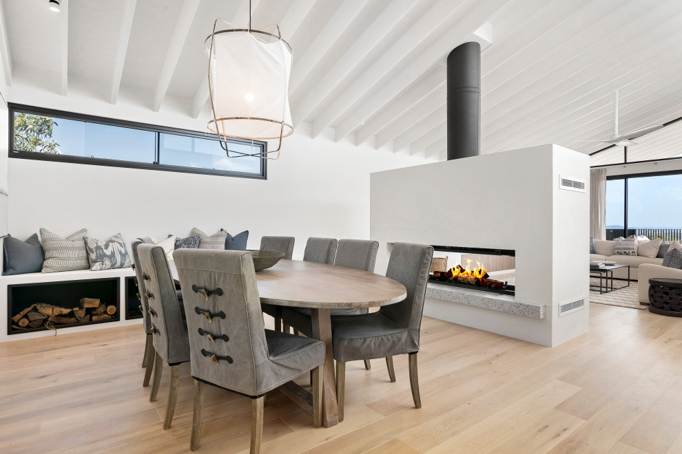 Photo of a large beach style open plan dining in Sydney with white walls, light hardwood floors, a ribbon fireplace, beige floor and vaulted.