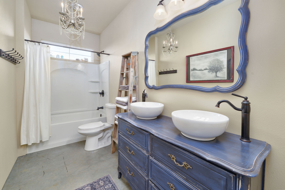 This is an example of a country 3/4 bathroom in Other with raised-panel cabinets, distressed cabinets, a shower/bathtub combo, a two-piece toilet, beige walls, a vessel sink, wood benchtops, a shower curtain, blue benchtops, a double vanity and a built-in vanity.
