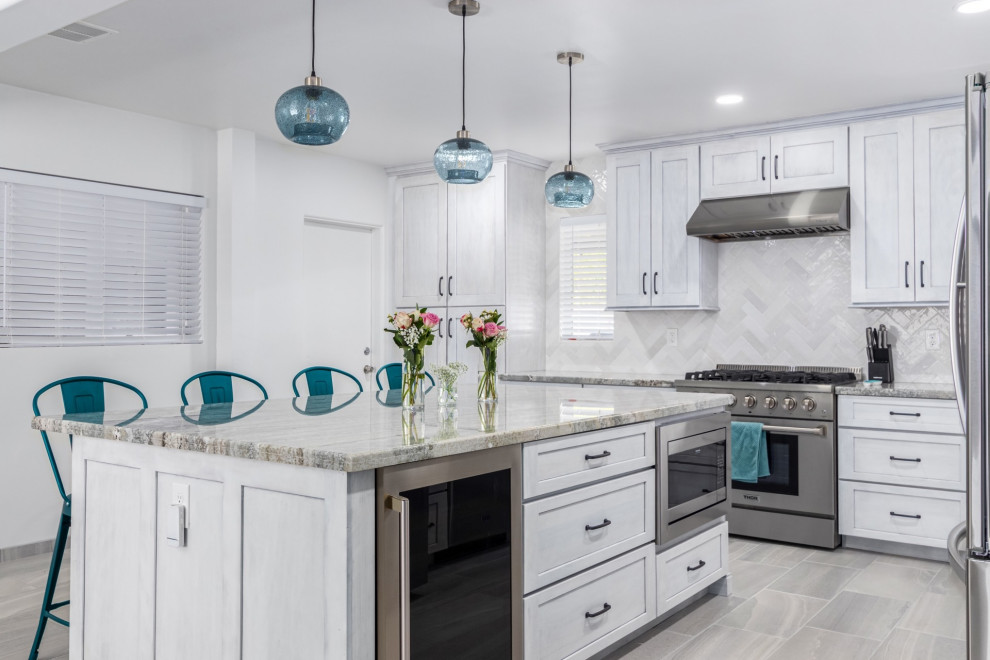 Transitional l-shaped kitchen photo in Phoenix with a single-bowl sink, shaker cabinets, white cabinets, granite countertops, white backsplash and stainless steel appliances