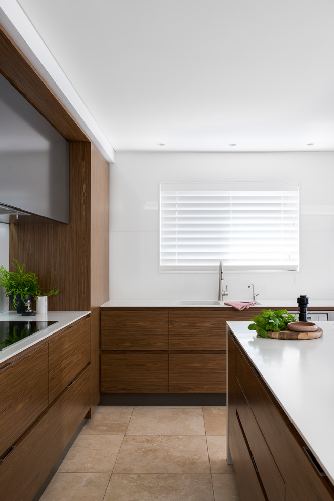 Inspiration for a mid-sized modern l-shaped open plan kitchen in Sydney with a double-bowl sink, flat-panel cabinets, medium wood cabinets, solid surface benchtops, white splashback, glass sheet splashback, stainless steel appliances, limestone floors, with island and beige floor.