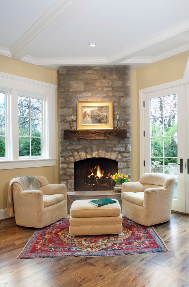 Photo of a living room in Columbus with yellow walls, dark hardwood floors, a corner fireplace and a stone fireplace surround.