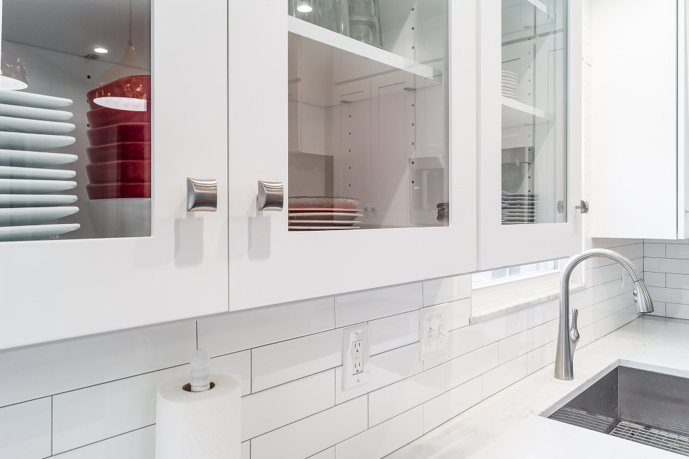 Example of a mid-sized transitional l-shaped eat-in kitchen design in Columbus with shaker cabinets, quartz countertops, white backsplash, subway tile backsplash and an island