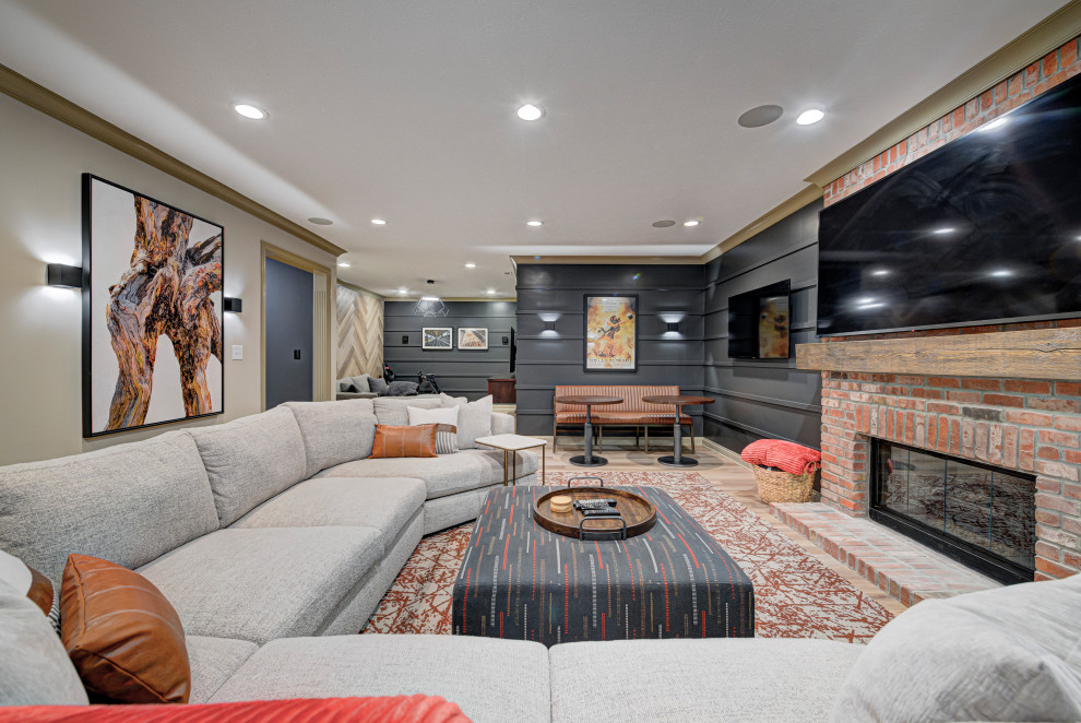 Design ideas for a medium sized contemporary fully buried basement in Indianapolis with a standard fireplace, grey walls, light hardwood flooring, a brick fireplace surround, brown floors and panelled walls.