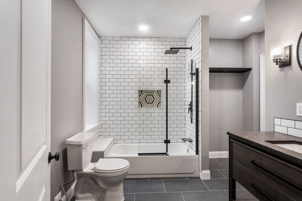 Design ideas for a large modern ensuite bathroom in Philadelphia with white tiles, metro tiles, porcelain flooring, engineered stone worktops, grey floors, a hinged door, black worktops, a laundry area and a single sink.