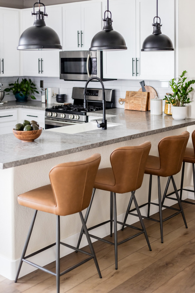 Mittelgroße Moderne Wohnküche in U-Form mit Landhausspüle, Schrankfronten im Shaker-Stil, weißen Schränken, Küchenrückwand in Weiß, Rückwand aus Metrofliesen, Laminat und braunem Boden in San Diego