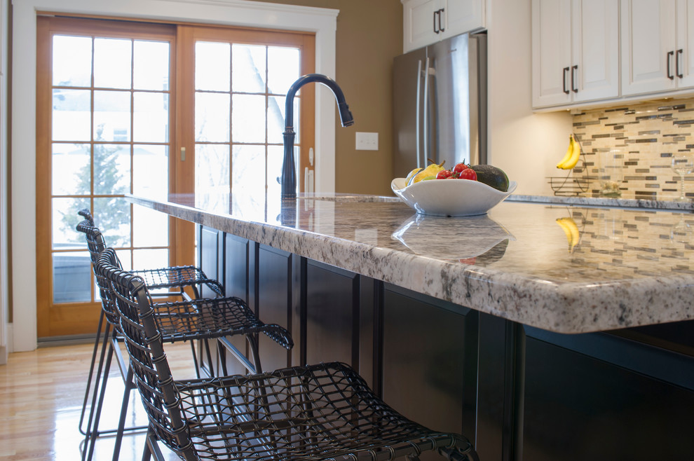 Eat-in kitchen - mid-sized transitional galley light wood floor eat-in kitchen idea in Boston with an undermount sink, raised-panel cabinets, white cabinets, granite countertops, multicolored backsplash, ceramic backsplash, stainless steel appliances and an island