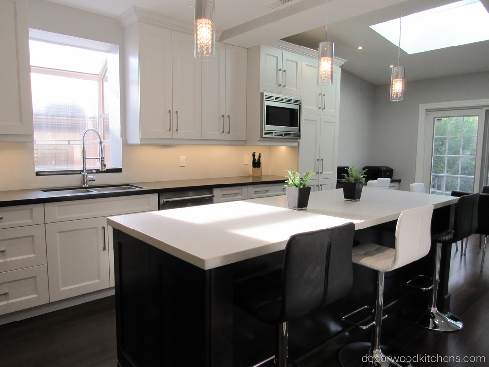 Enclosed kitchen - large transitional l-shaped dark wood floor enclosed kitchen idea in Toronto with an undermount sink, shaker cabinets, white cabinets, quartz countertops, white backsplash, stone slab backsplash, stainless steel appliances and an island