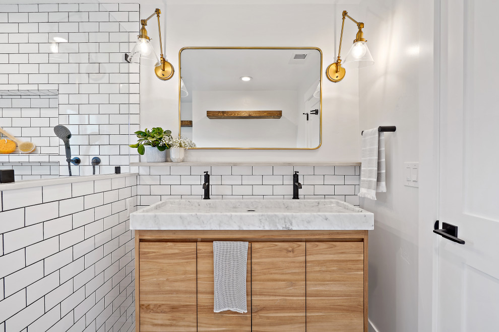 Inspiration for a transitional 3/4 bathroom in San Francisco with flat-panel cabinets, light wood cabinets, white tile, subway tile, white walls, a trough sink and a double vanity.