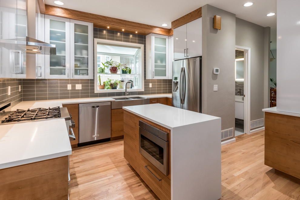Design ideas for a mid-sized contemporary u-shaped eat-in kitchen in Denver with a farmhouse sink, white cabinets, quartz benchtops, grey splashback, glass tile splashback, stainless steel appliances, light hardwood floors, with island, flat-panel cabinets and beige floor.