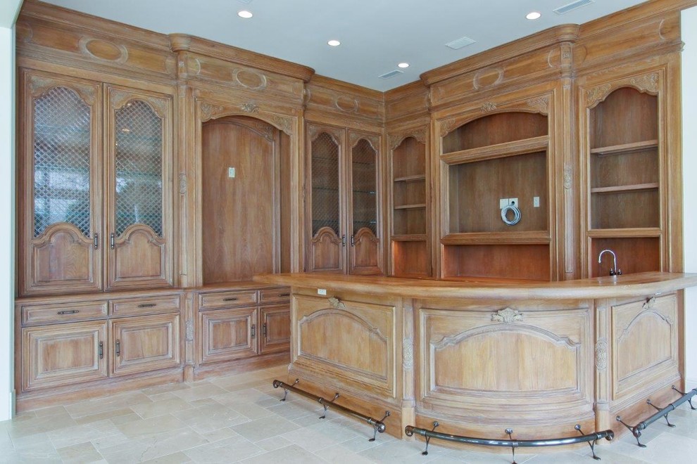 Photo of a large traditional l-shaped seated home bar in Miami with raised-panel cabinets, dark wood cabinets, wood benchtops, brown splashback, timber splashback, limestone floors and grey floor.