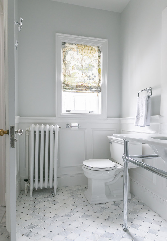 Elegant white tile and marble tile marble floor, white floor, double-sink and wainscoting doorless shower photo in Baltimore with white cabinets, a two-piece toilet, white walls, a pedestal sink, marble countertops, a hinged shower door, white countertops and a niche