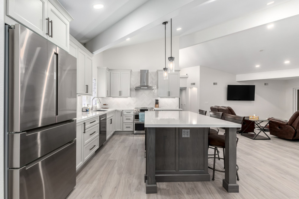 Example of a mid-sized transitional porcelain tile and gray floor eat-in kitchen design in Phoenix with an undermount sink, shaker cabinets, gray cabinets, quartz countertops, white backsplash, subway tile backsplash, stainless steel appliances, an island and white countertops