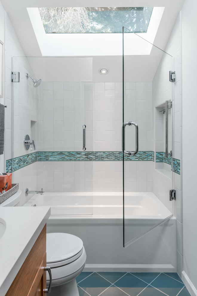 Design ideas for a small beach style master bathroom in San Francisco with shaker cabinets, brown cabinets, an alcove tub, a shower/bathtub combo, a two-piece toilet, blue tile, ceramic tile, blue walls, ceramic floors, an undermount sink, engineered quartz benchtops, blue floor and a hinged shower door.