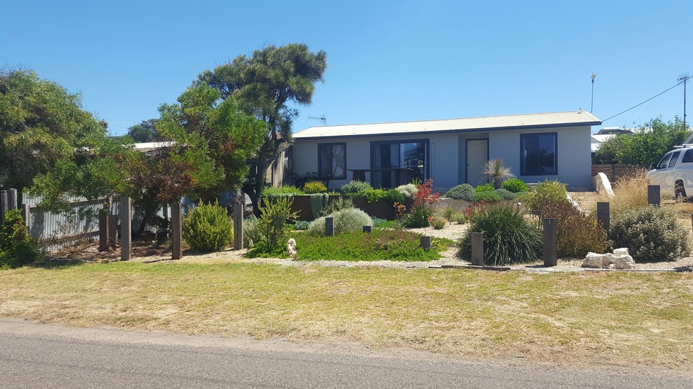 This is an example of a mid-sized and australian native beach style front yard full sun xeriscape in Adelaide with a garden path and gravel.