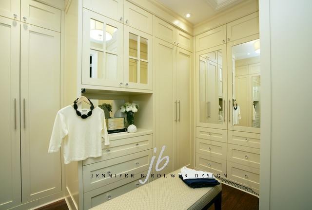 This is an example of a mid-sized contemporary women's walk-in wardrobe in Toronto with shaker cabinets, white cabinets and dark hardwood floors.