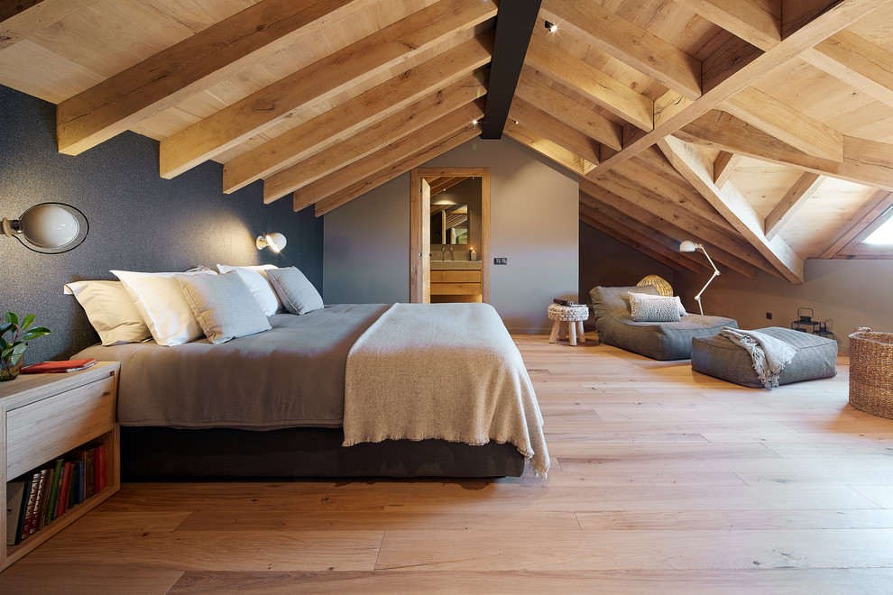 Photo of a large country guest bedroom in Other with light hardwood floors, grey walls and beige floor.