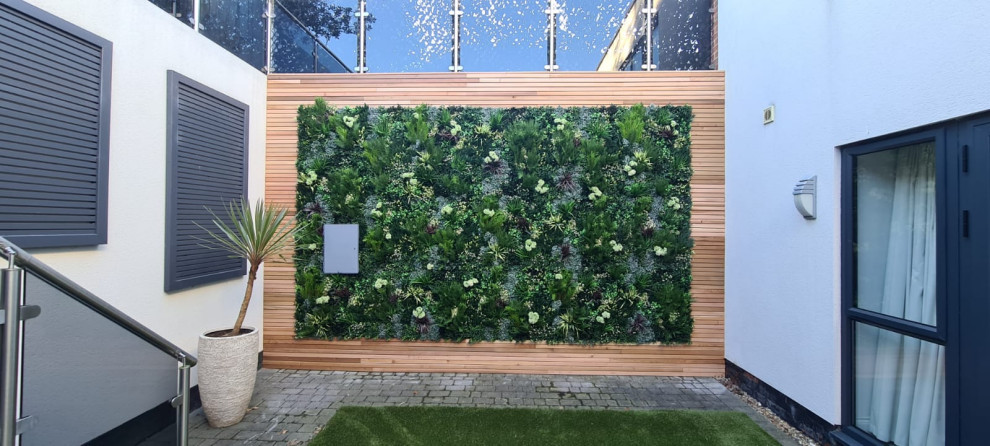 Photo of a medium sized modern courtyard formal partial sun garden for summer in London with a living wall and decking.