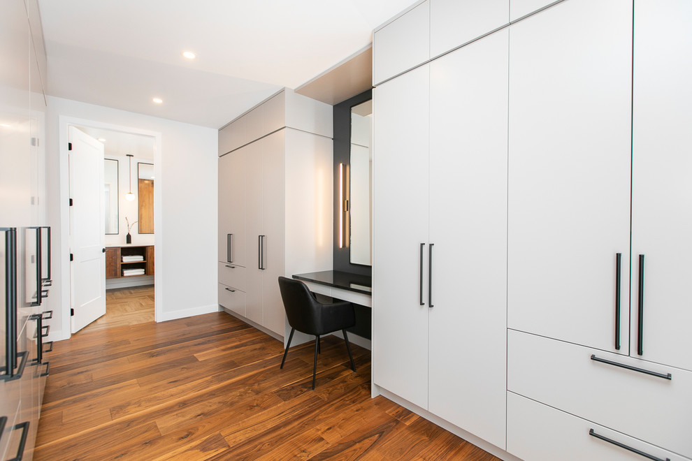 Photo of an expansive contemporary gender-neutral walk-in wardrobe in Ottawa with flat-panel cabinets, grey cabinets, medium hardwood floors and brown floor.
